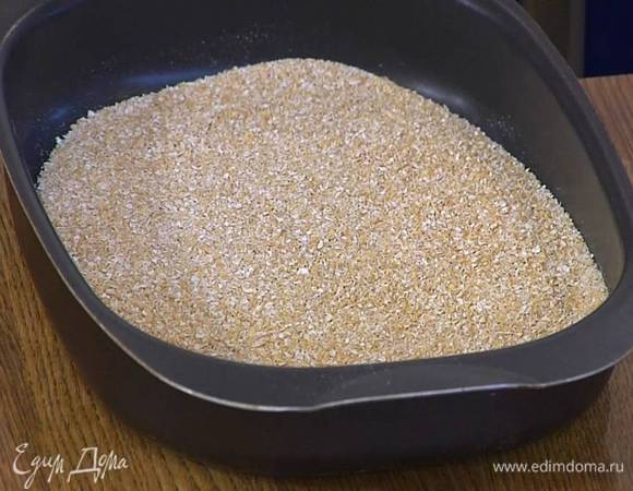 Отруби всыпать в глубокий противень и подсушивать в разогретой до 150°С духовке 10‒15 минут.