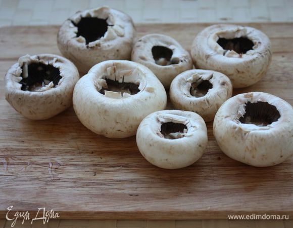 Тщательно очистите шампиньоны от земли и аккуратно вырежьте их ножки (не выбрасывайте их, они пойдут в начинку).