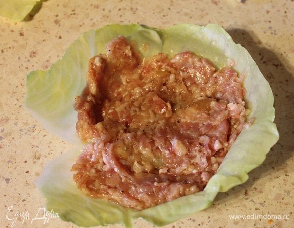 На остывший лист капусты выложить 1-2 ст. л. фарша, разровнять его.
