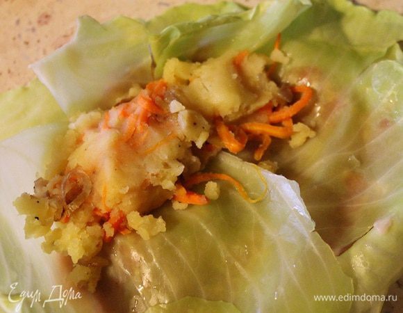 Сверху накрыть еще одним листом капусты и ближе к краю положить начинку из картофеля и овощей.
