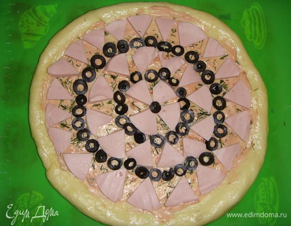 Колбасу произвольно нарезать, маслины нарезать кружочками. Выложить все на тесто.