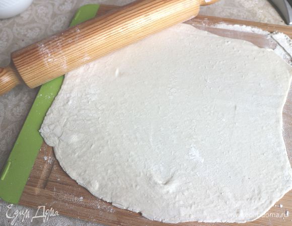 Духовку разогреть до 190°С. Раскатать тесто на поверхности, присыпанной мукой. Необходимо два круга из теста. Вырезать один круг из раскатанного теста по размеру формы. Другой круг должен быть большего размера (для дна и бортиков).