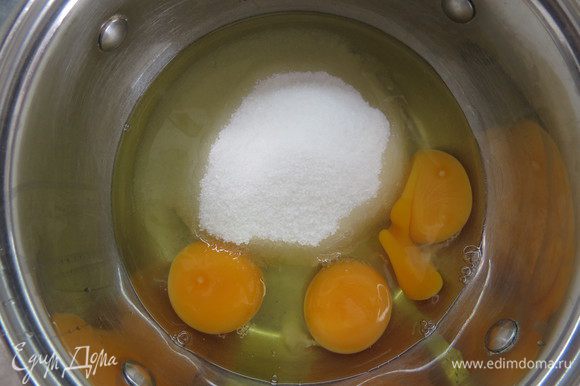 Готовим заварной бисквит Женуаз. Организуем водяную баню: в одну кастрюльку наливаем воду и ставим на огонь, на эту кастрюльку водружаем вторую. Кипящая вода в первой кастрюльке не должна касаться дна второй кастрюли. Во вторую кастрюльку помещаем 3 яйца и сахар. Взбиваем яичную смесь на малой скорости миксера до полного растворения сахара.