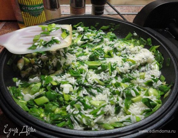 Разогреть сливочное и оливковое масло в глубокой сковороде и вначале спассеровать зеленый лук, затем добавить рис и слегка его обжарить, минуты 3. За это время он впитает масло и станет немного прозрачным.