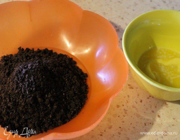 К крошке печенья добавить растопленное масло и тщательно перемешать. Дно разъемной формы (18 см) застелить пергаментом и выложить крошку печенья с маслом. Разровнять руками. Поставить в заранее разогретую до 160°С духовку на 15 минут. Готовый корж остудить.

