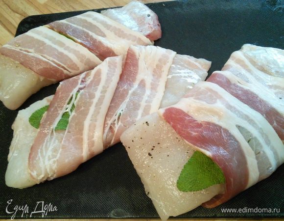 Самое кропотливое занятие в этом рецепте — разделать судака на филе, но когда это будет сделано, то останутся считанные минуты, и блюдо будет готово. Итак, филе судака посолить и поперчить, выложить с каждой стороны по листику шалфея и обернуть беконом. Бекон — это бюджетный вариант пармской ветчины :)  