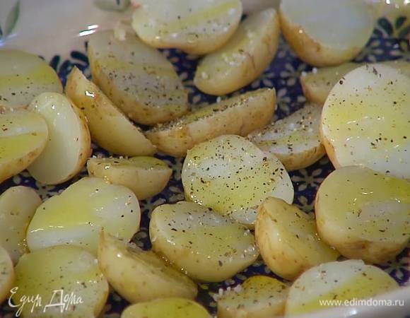 Готовый картофель, не очищая, разрезать пополам (более крупный — на 4 части), выложить в жаропрочную форму разрезами вверх, посолить, поперчить и полить половиной оливкового масла.