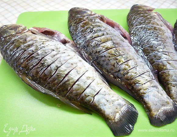 Карасей надрезаем с обеих сторон, натираем маринадом внутри и снаружи, оставшимся маринадом заливаем рыбу и оставляем на 20 минут.