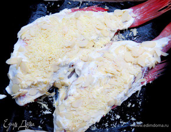 Выкладываем рыбу в огнеупорную форму на пергамент или коврик для запекания (можно сделать подушку из лука). Обмазываем окуня готовым соусом, сверху посыпаем тертым пармезаном и миндальными лепестками.