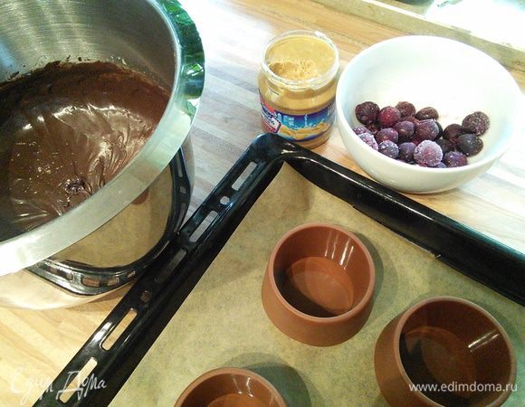 В конце аккуратно по стенке тонкой струйкой, не прекращая взбивать, влить растопленное сливочное масло. Тесто готово. Приготовить ягоду. Я заменила малину на вишню, использовала сразу замороженную. Ореховую пасту можно брать любую, главное, чтобы она была густой. Чем гуще паста, тем лучше она будет держаться в десерте. Формочки необходимо смазать маслом и посыпать мукой. У меня силиконовые, поэтому я их не смазывала. 