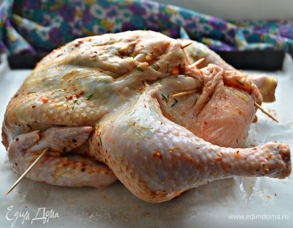 Отверстие курицы зашейте или скрепите зубочистками, крылья подверните внутрь и закрепите зубочистками, чтобы не обгорали. Выложите тушку на противень грудкой вверх и запекайте при 180°С 1-1,15 ч. Если курочка быстро подрумянивается, прикройте ее фольгой.