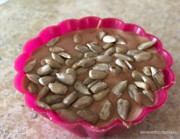 Формочки наполовину заполнить тестом, добавить халву, снова добавить тесто и украсить семечками. 