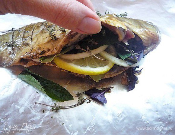 По истечении времени рыбу укладываем на лист фольги, в брюшко кладем дольки лимона, кольца лука, лавровый лист, листики мяты и базилика. Сверху посыпаем солью, перцем и тимьяном.