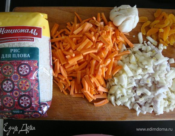 Рис ТМ «Националь» промыть в нескольких водах до прозрачной воды. Морковь нарезать соломкой, лук — кубиками, курагу нарезать тонкими полосками, с чеснока снять верхний слой и срезать хвостик.