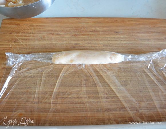 Разложить пищевую пленку на разделочную доску, выложить куриный фарш, свернуть, отрезать пленку ножом по разделочной доске и скрутить края. 