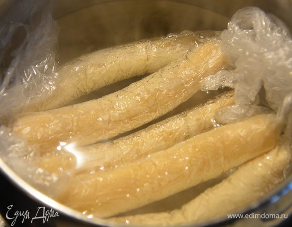 Выложить сосиски в кипящую воду. Длинные края пленки можно срезать.