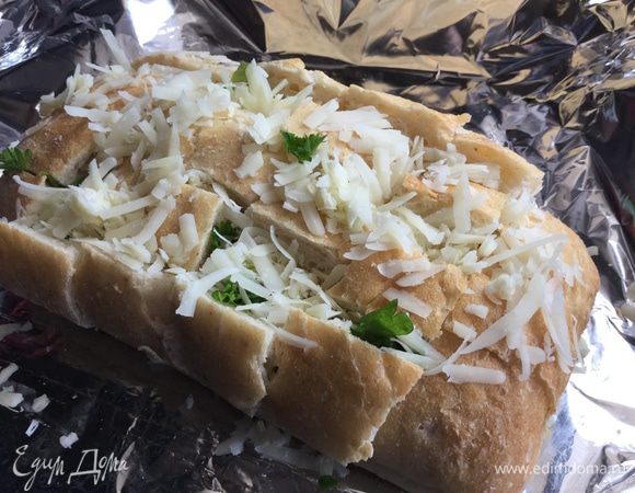 Начините хлеб чесноком, сыром и зеленью и заверните в фольгу.