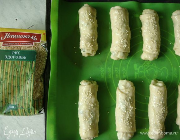 Выложить пирожки на силиконовый коврик (или пергамент), смазать взбитым яйцом и посыпать кунжутом. Поставить противень с пирожками в разогретую до 190°С духовку на 25-30 минут.