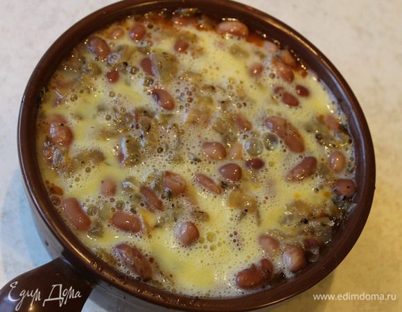 Залейте фасоль луковым бульоном. Взбейте яйца и залейте суп. Отправьте суп в горячую духовку томиться до готовности.