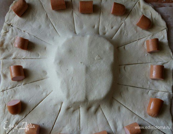 Выкладываем по кругу равномерно. Делаем разрезы между сосисками.