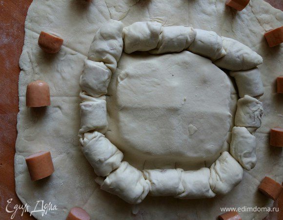 Сворачиваем рулетики, убираем пергамент и вновь раскладываем сосиски как раз по выемке, получившейся от разрезания первого ряда. 