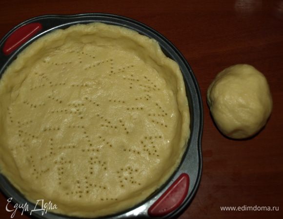 Предварительно по диаметру формы вырезать из пекарской бумаги круг и застелить им дно формы. Смазать растительным маслом. Тесто достать из холодильника и дать постоять 10 минут. Затем раскатать на посыпанной мукой поверхности не толстый пласт и выложить им форму для выпечки. Лишнее тесто убрать. Проткнуть корж вилкой в нескольких местах (не скупясь). Отправить корж в заранее разогретую духовку до 180°С на 10 минут. У меня форма диаметром 20 см, глубина — 4,5 см. Осталось тесто, из которого получается вкусное печенье. 