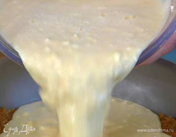 В разъемную форму для выпечки высыпать бисквитную крошку и утрамбовать руками, сверху влить творожную начинку.