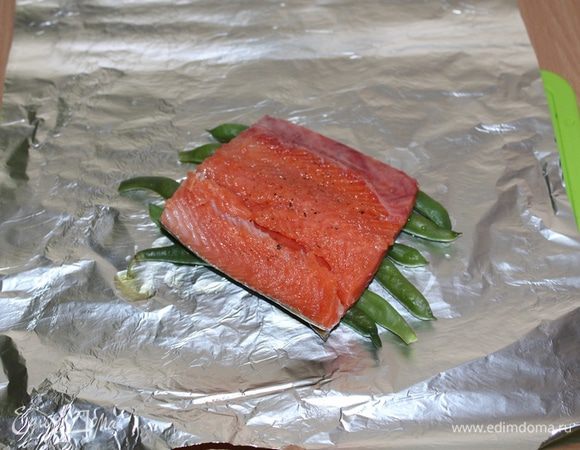 На фольгу выложить (отваренную 2-3 минуты) фасоль, сверху кусочек рыбы шкуркой вниз.