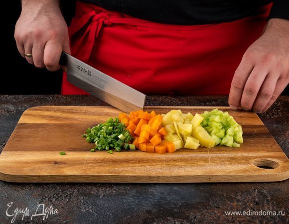 Отварите морковь и картофель. Нарежьте кубиками. Нарежьте очищенные огурцы и измельчите зеленый лук. 