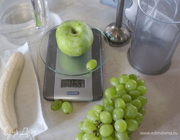 Подготовить фрукты: очистить банан, яблоко, удалить его сердцевину. Порезать фрукты на кусочки, положить в высокую емкость. Добавить горсть винограда и 50 мл воды. Взбить блендером до однородной массы. 