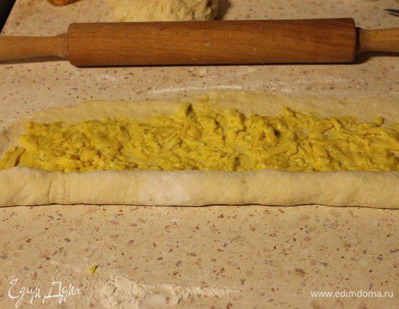 Самый большой кусок теста, т. е. ровную половину, раскатать в длину 55 см и в ширину 20 см. Выложить начинку №1, разровнять. Скатать рулетом, защипать края.
