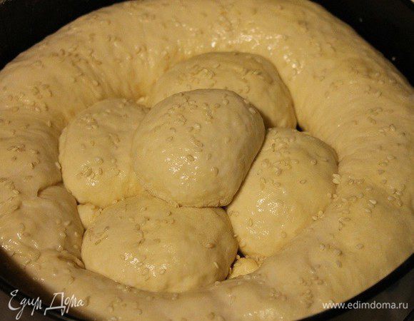 Во внутрь ободка-рулета выложить шарики с начинкой. Накрыть полотенцем и дать постоять 30 минут. Верх пирога смазать 2 ст. л. молока и посыпать кунжутом. Выпекать в заранее разогретой до 200°С духовке 30-40 минут.

