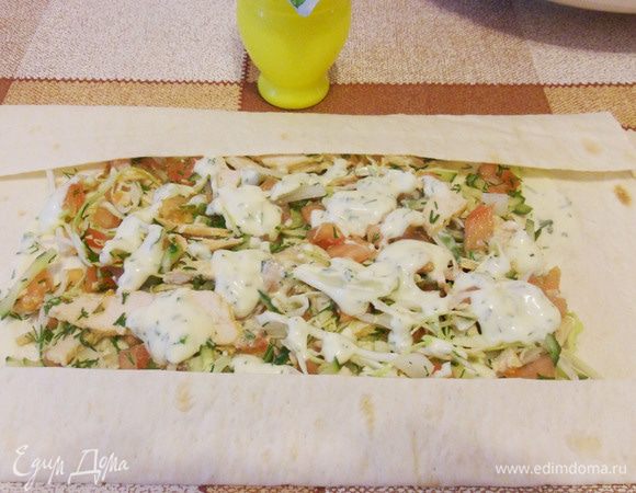 Затем, отступив от краев лаваша, выложить начинку, полить соусом, края лаваша завернуть в виде конверта и аккуратно свернуть рулетом.