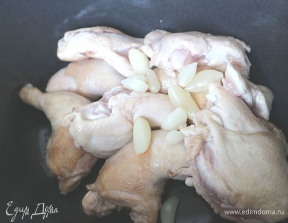 Положить обжаренного цыпленка в жаровню, добавить чеснок целыми зубчиками.