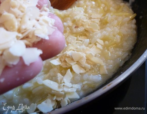 Когда рис будет почти готов, всыплем миндальные лепестки, часть пармезана. Перемешаем, добавим сливочное масло, накроем крышкой и оставим на пару минут.