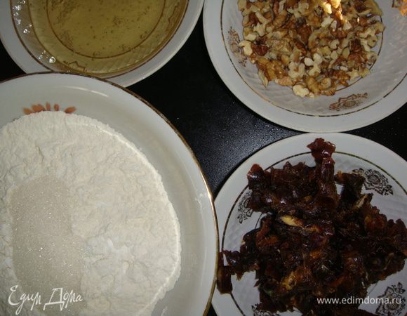 Финики помыть и залить водой, поставить в микроволновку на 2 минуты. Слить с них воду, нам надо 200 мл теплой воды. У фиников вынуть косточки, мякоть порезать ножом на небольшие кусочки. Грецкие орехи порубить ножом. В чашку просеять муку, соду, добавить сахар, ванильный сахар, перемешать.