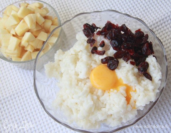 Яблоко очистить от кожуры, нарезать кубиком. В рис добавить желток, клюкву вместе в коньяком.