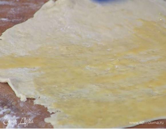 Желток посолить, перемешать с молоком и кисточкой смазать пласт теста.