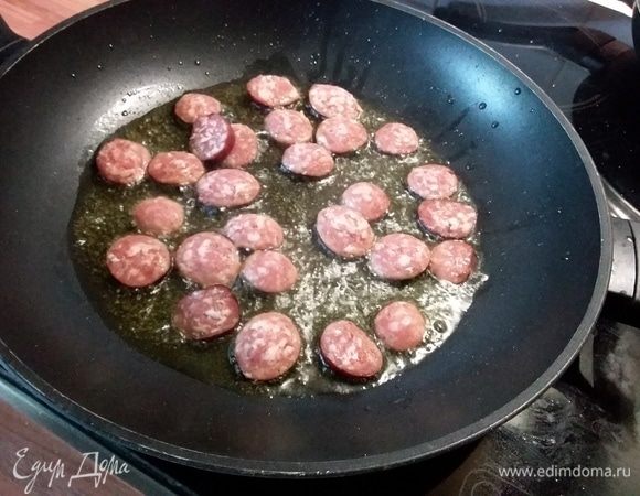 Разогреть оливковое масло в жаровне, добавить чоризо. Обжарить, помешивая, пока колбаса слегка не подрумянится, примерно 5-7 минут. 
