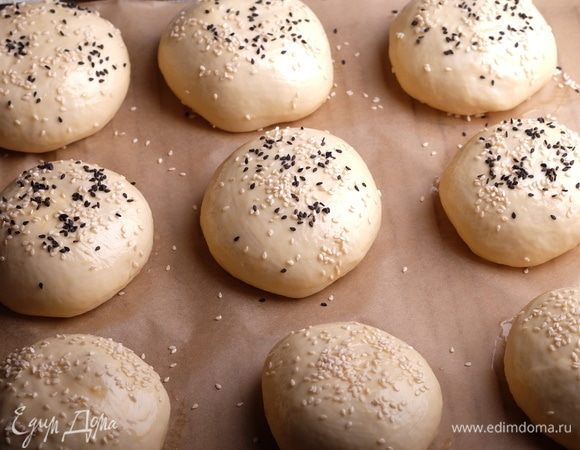 Духовку разогреть до 200°С. Смешать яйцо с водой, смазать каждую булочку и посыпать кунжутом.