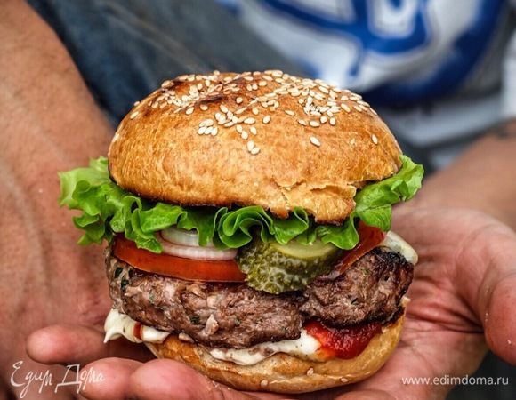 Собираем бургер. На нижнюю половинку булочки намазать кетчуп, майонез, горчицу, далее положить котлету, на еще горячую котлету — пластинку сыра, на сыр — ломтик помидора, на него маринованный лучок, далее — пару ломтиков маринованного огурчика, сверху листик салата и закончить все верхней половинкой булочки.