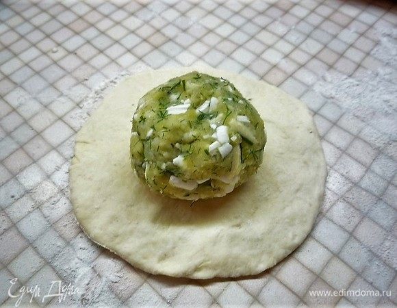 Раскатываем шарик теста в небольшую лепешку и кладем на нее начинку.
