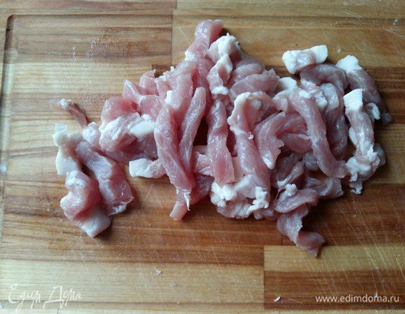 Порежем свинину на тонкие полосочки. Это мы делаем для быстроты приготовления супа. Можно, конечно, сварить мясо целиком, не нарезая на кусочки, а лишь потом порезать, но тогда процесс варки займет более продолжительное время. 