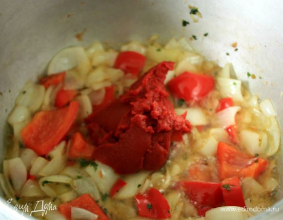 В казан положить лук, сладкий перец и чили, оставшийся чеснок, обжарить и добавить томатную пасту. 