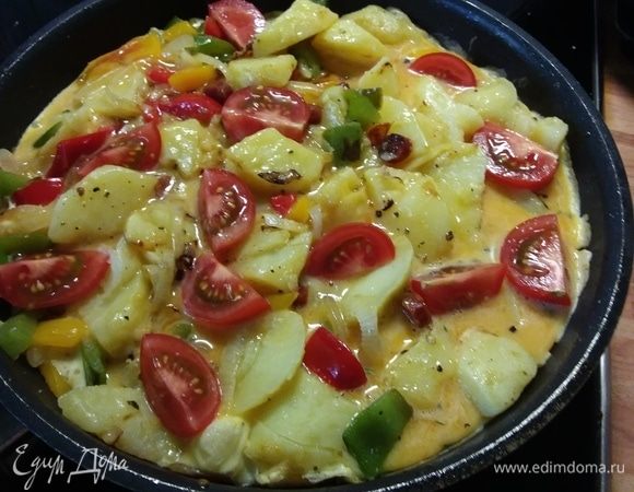 Залить яйцами, разложить помидоры. Когда вы увидите, что бока тортильи начинают схватываться, время ставить ее в духовку. 