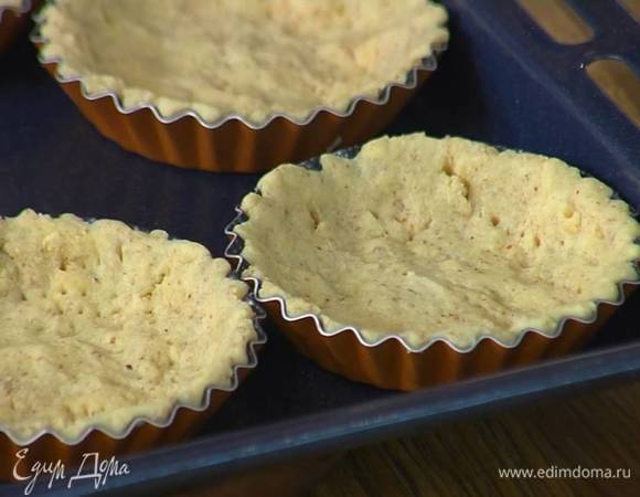 Тонким слоем выложить тесто в формочки для тарталеток, поместить на противень, часто наколоть тесто вилкой и отправить в разогретую духовку на 7‒10 минут.