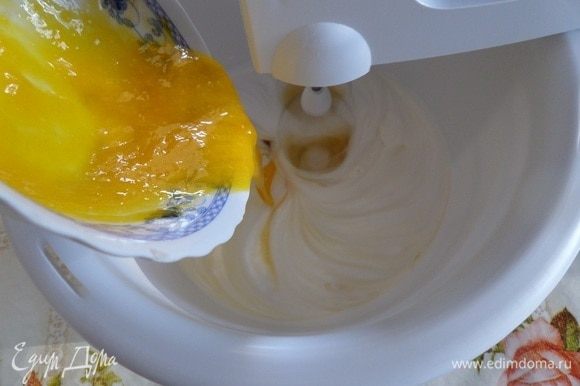 В чашку к взбивающимся белкам добавляем желтки.