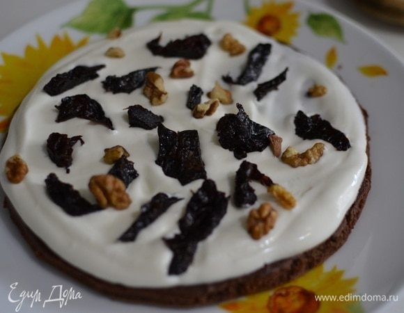 Собираем торт. Корж выложить на тарелку и распределить по нему часть сметанного крема, сверху выложить часть чернослива и орехов, тоже самое проделываем с остальными коржами.