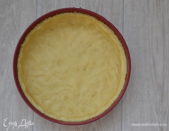 Достать тесто из холодильника, форму смазать маслом, выложить тесто в форму, делая бортики. Либо можно раскатать тесто на рабочей поверхности, присыпав мукой, вырезать круг по форме, прибавляя к диаметру несколько см для бортиков, и перенести с помощью скалки в форму.

