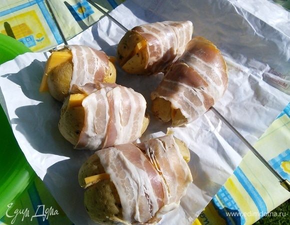 Соберите половинки картофеля вместе и оберните каждую картошку двумя полосками бекона. Нанизать на шампура, а можно и просто выложить картофель на гриль.  